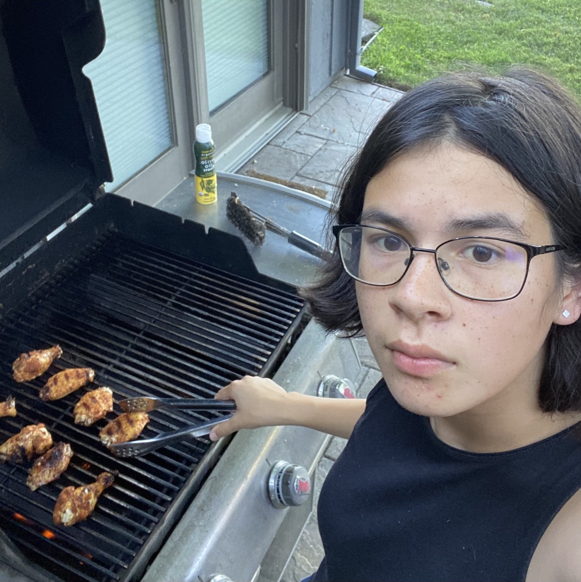 Me, Miriam, taking a selfie with some chicken wings on a grill.
